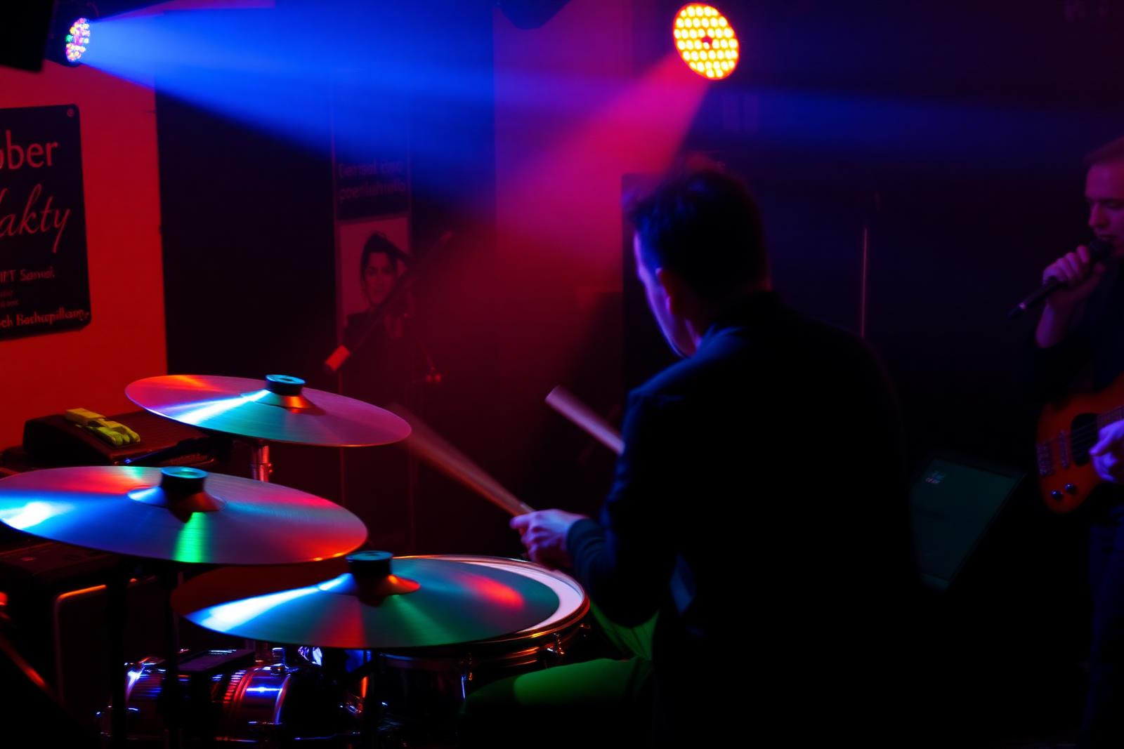 Drummer playing at a small live music venue with stage lighting